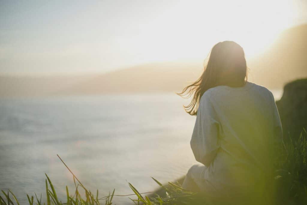2026 wellness woman wearing gray long-sleeved shirt facing the sea