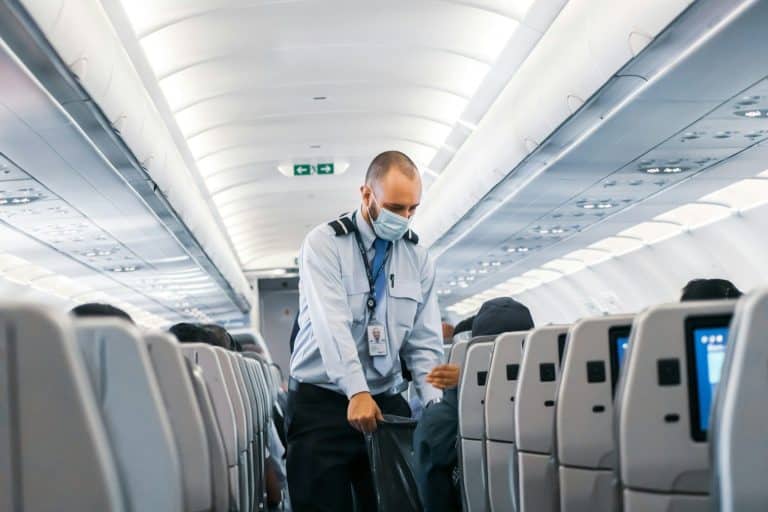 Economy Class man in blue dress shirt standing in airplane